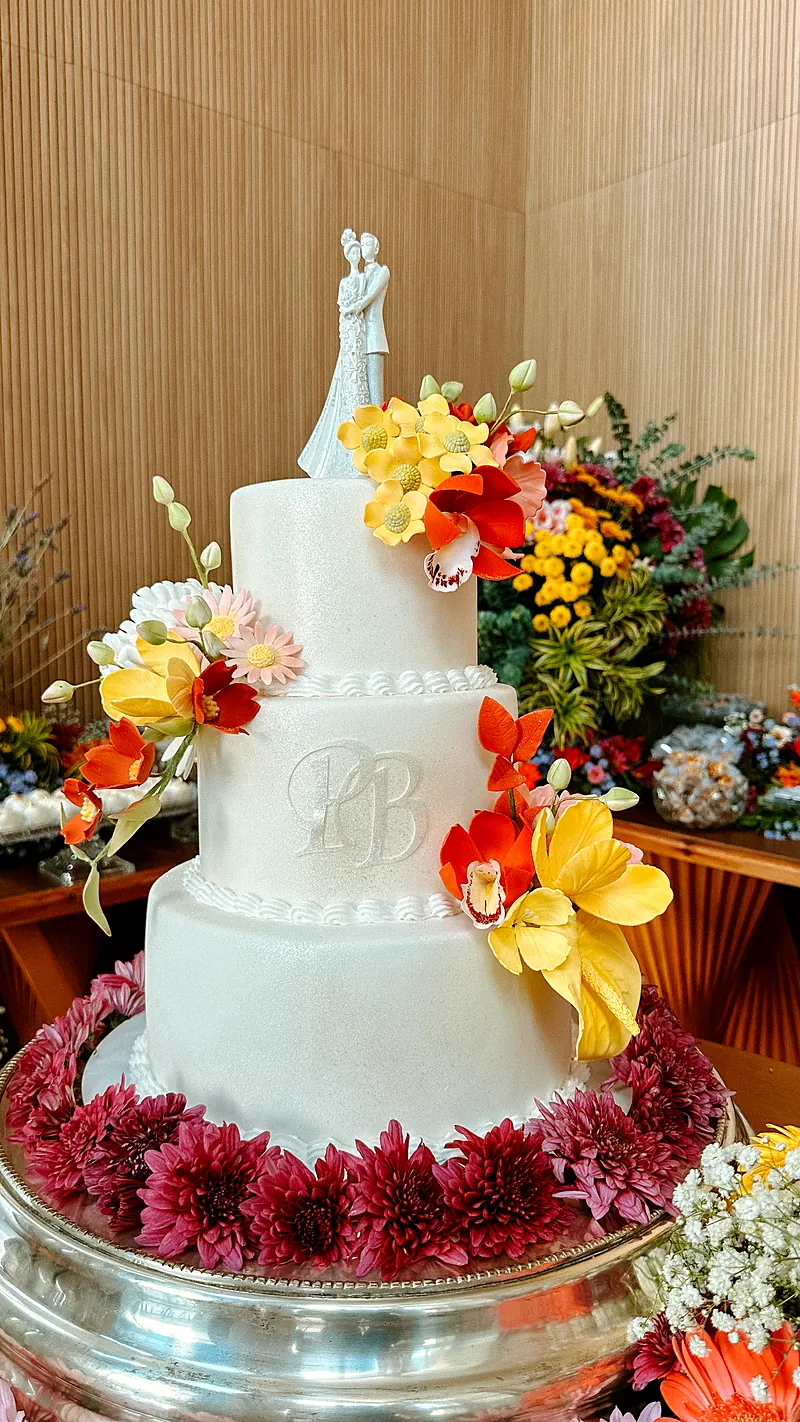 Bolo branco de três andares decorado com flores tropicais