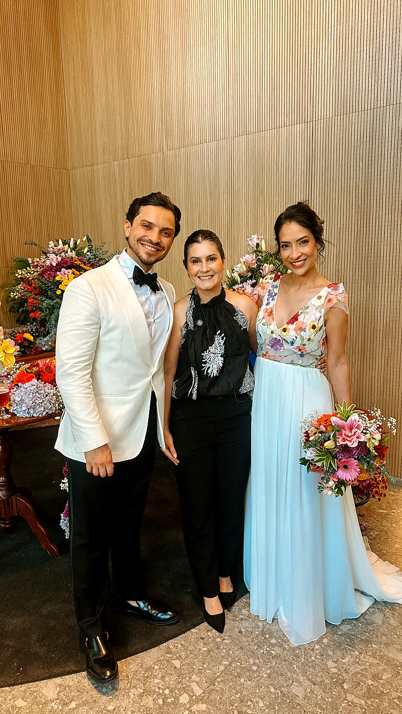 Bruna Dias com os noivos Bia e Paulinho em frente à mesa de doces