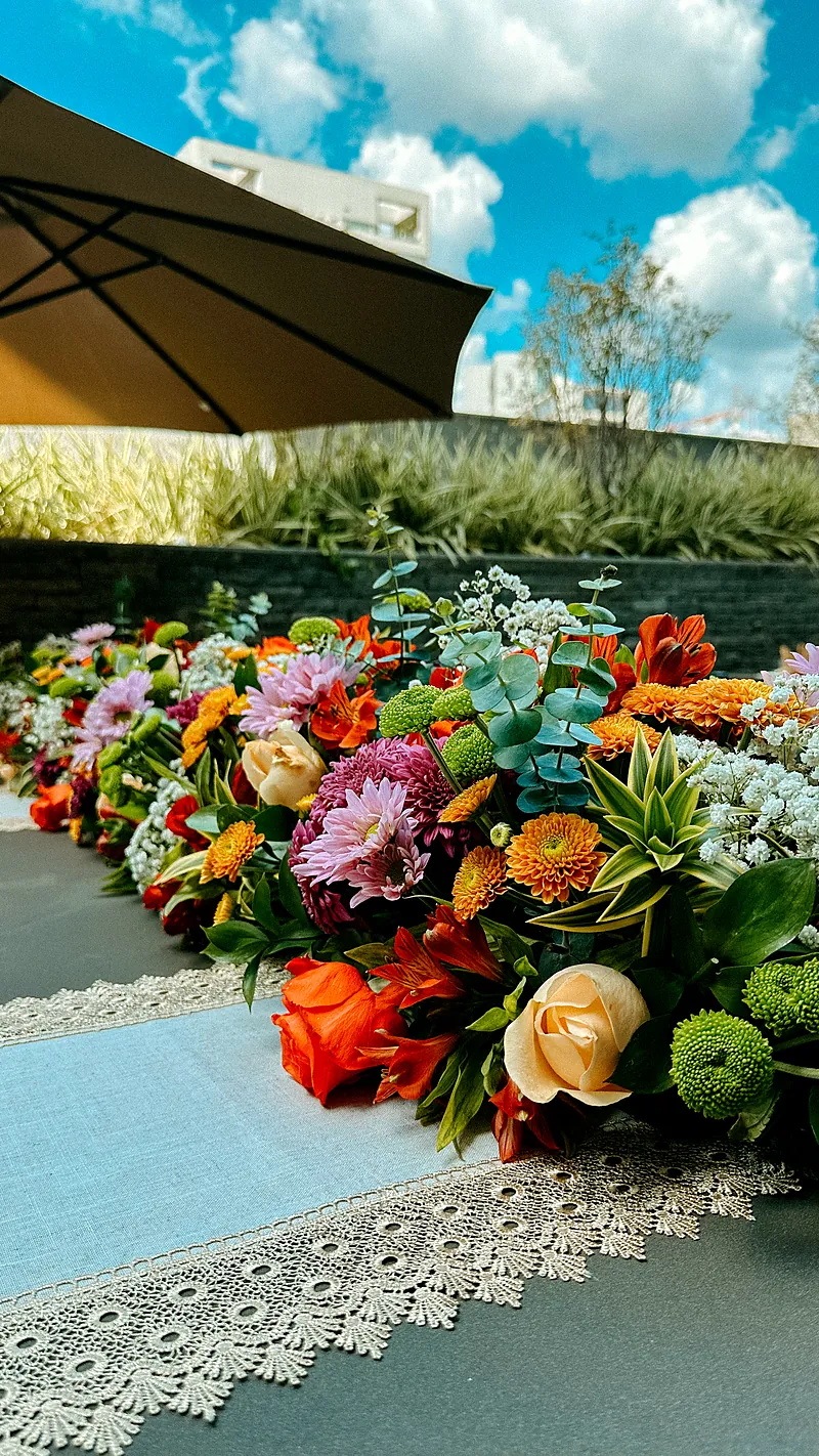 Mesa posta com arranjo baixo de flores laranja, rosa e amarelas